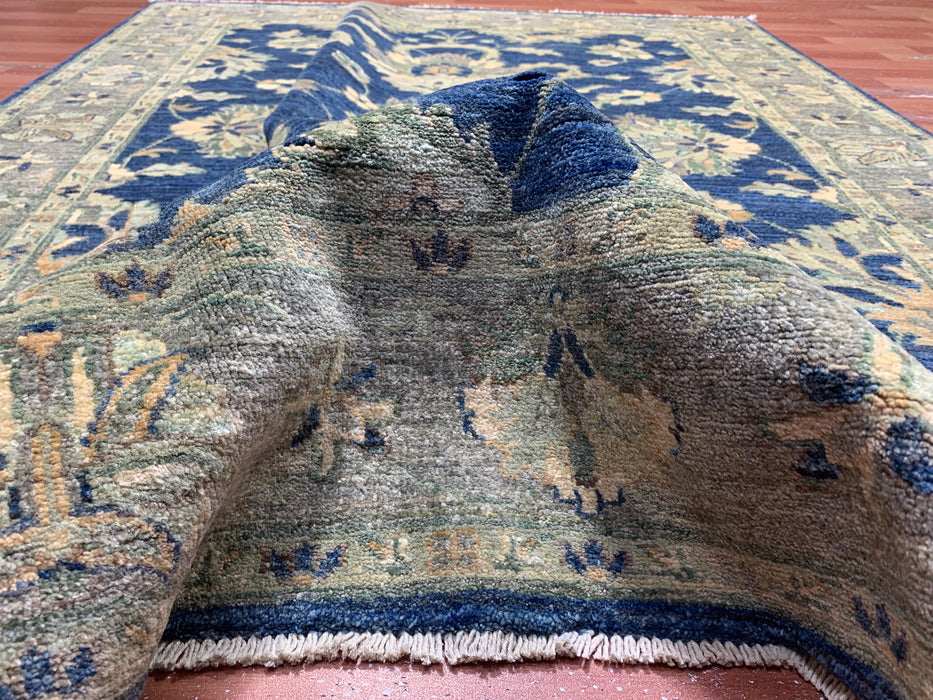147 × 198 cm handgeknoopt wollen tapijt – marineblauw met bloemrijke rand in zacht beige en saliegroen