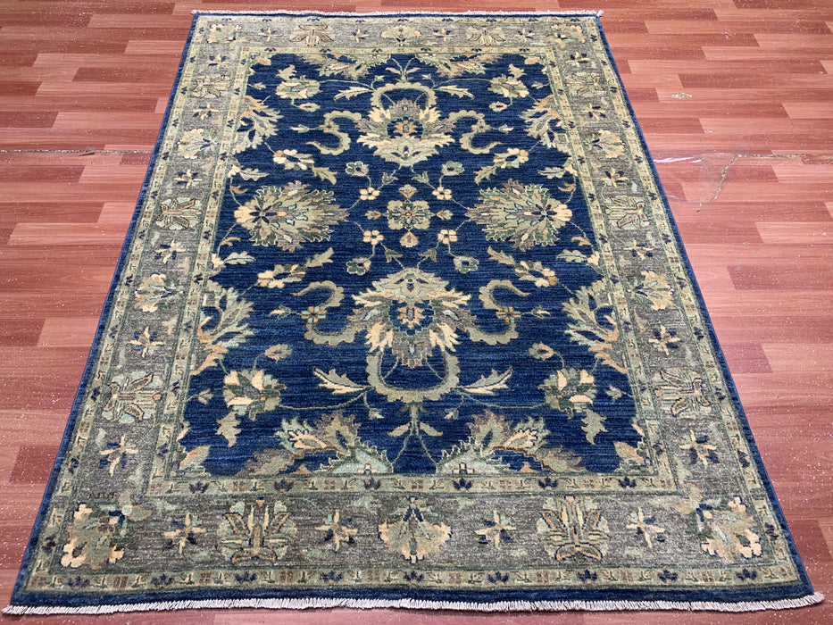 147 × 198 cm handgeknoopt wollen tapijt – marineblauw met bloemrijke rand in zacht beige en saliegroen