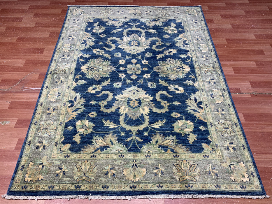 147 × 198 cm handgeknoopt wollen tapijt – marineblauw met bloemrijke rand in zacht beige en saliegroen