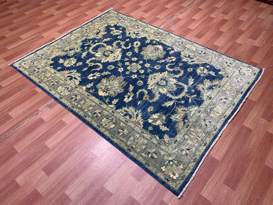 147 × 198 cm handgeknoopt wollen tapijt – marineblauw met bloemrijke rand in zacht beige en saliegroen