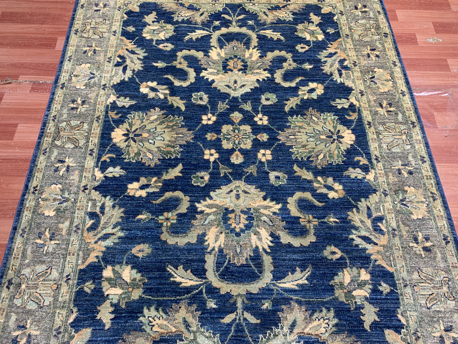 147 × 198 cm handgeknoopt wollen tapijt – marineblauw met bloemrijke rand in zacht beige en saliegroen