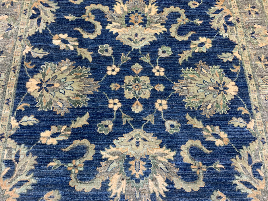 147 × 198 cm handgeknoopt wollen tapijt – marineblauw met bloemrijke rand in zacht beige en saliegroen