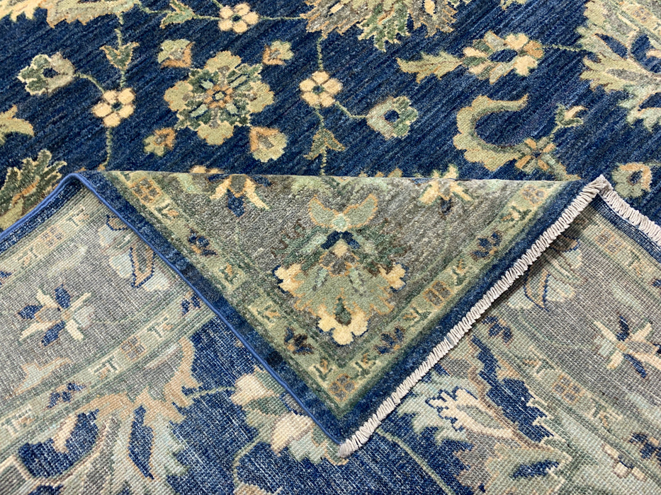 147 × 198 cm handgeknoopt wollen tapijt – marineblauw met bloemrijke rand in zacht beige en saliegroen